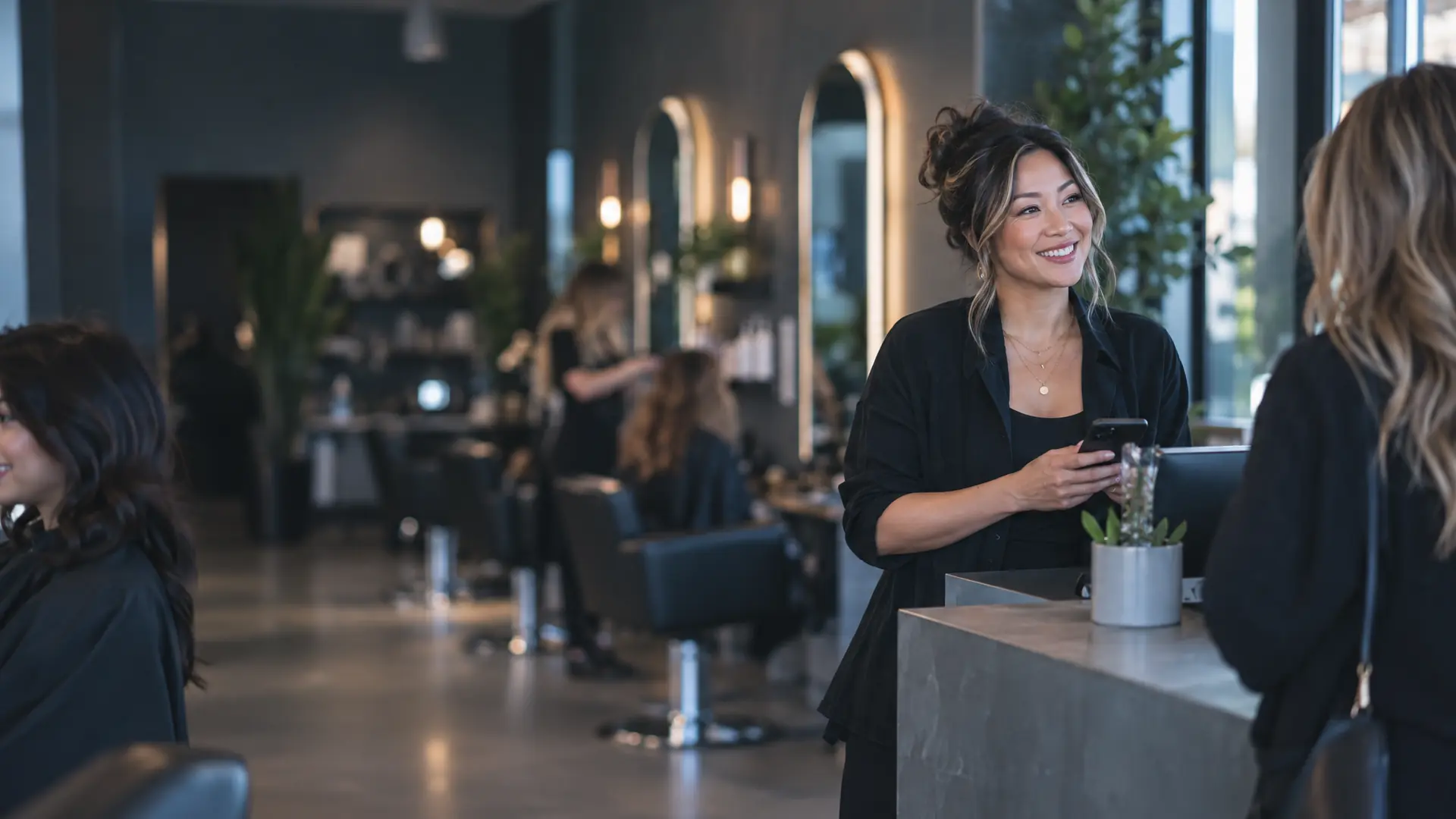 Hair salon owner at the reception desk holding her phone between clients