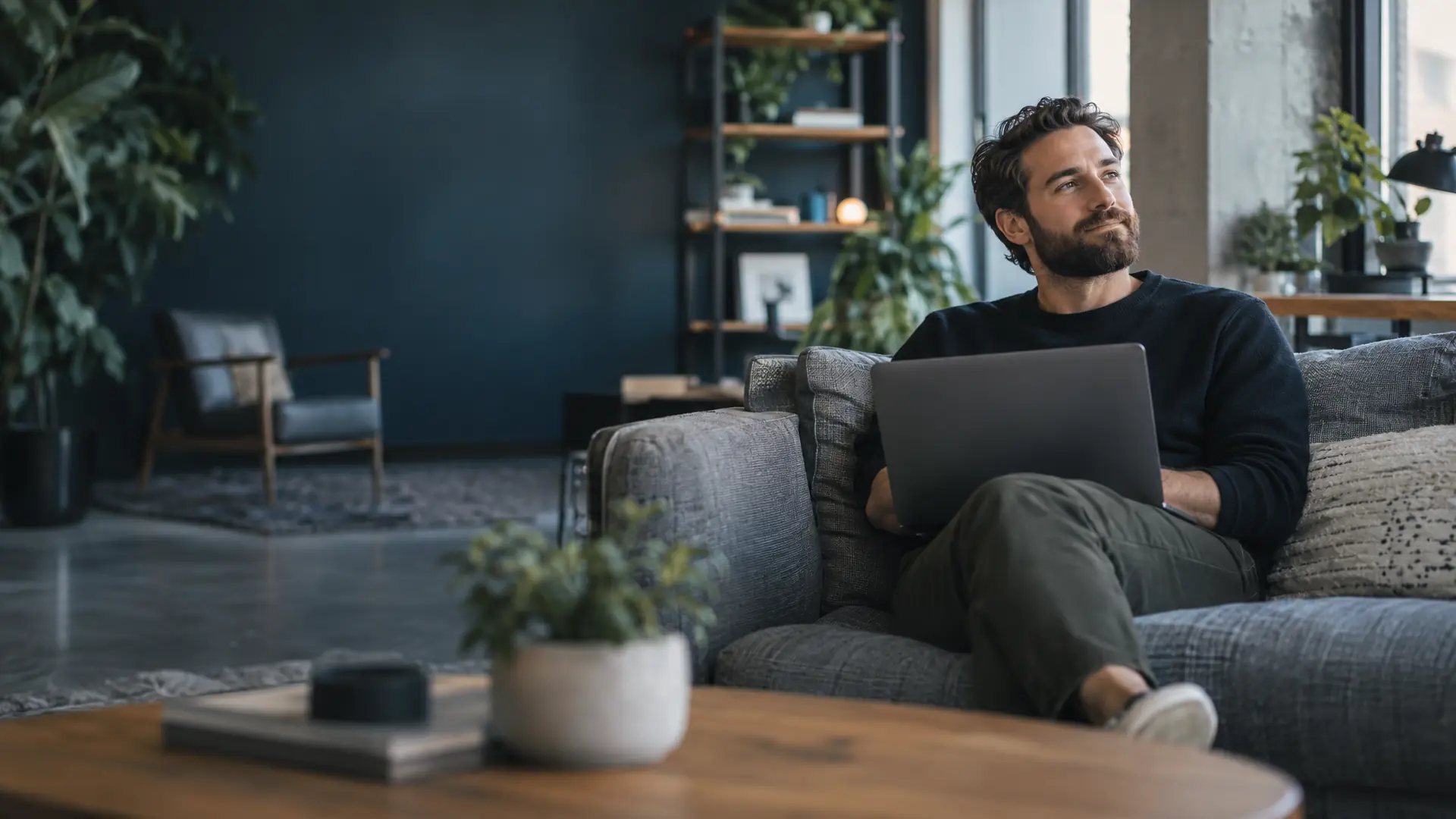 Software consultancy founder on a couch in a studio office with a laptop on his knees